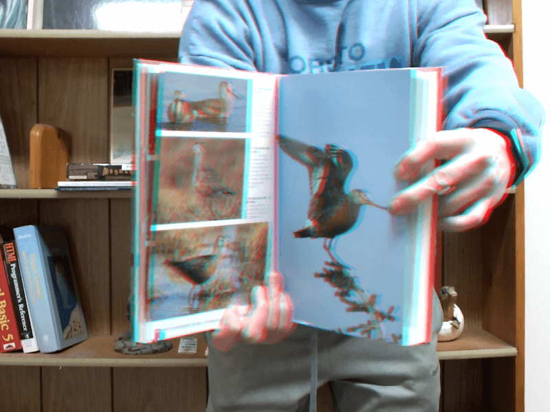 3D image of an open book held in front of me, creating the illusion of depth. The book appears to come out of the screen.