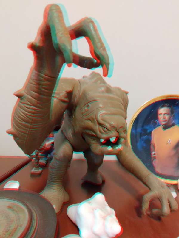 Three-dimensional photo of a toy Rancor. I extended the rancor's right arm forward. So it appears to be reaching out of the display. The depth illusion creates a near-real effect.